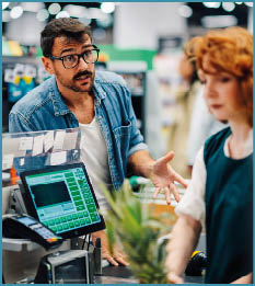 A man and woman are standing in front of a cash register. Description generated by AI