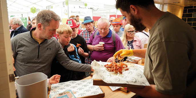 A man is cooking food in a kitchen while a crowd of people watches. AI generated content