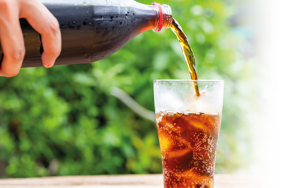 A person pouring a glass of soda with a bottle of soda behind it. AI generated content
