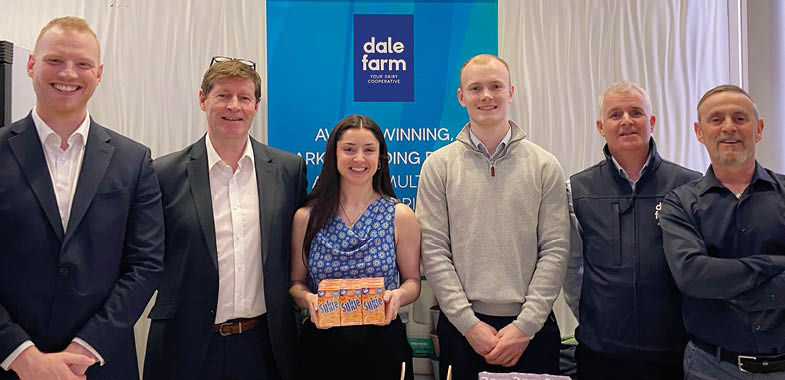A group of people are standing in front of a table with a box of candy on it. AI generated content