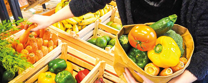 A person holding a basket of vegetables. Description generated by AI