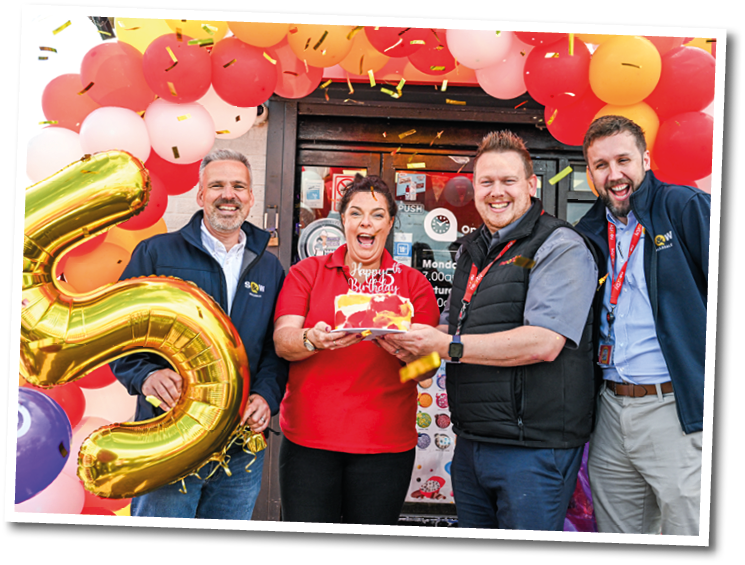 A group of people are standing in front of a balloon arch. Description generated by AI