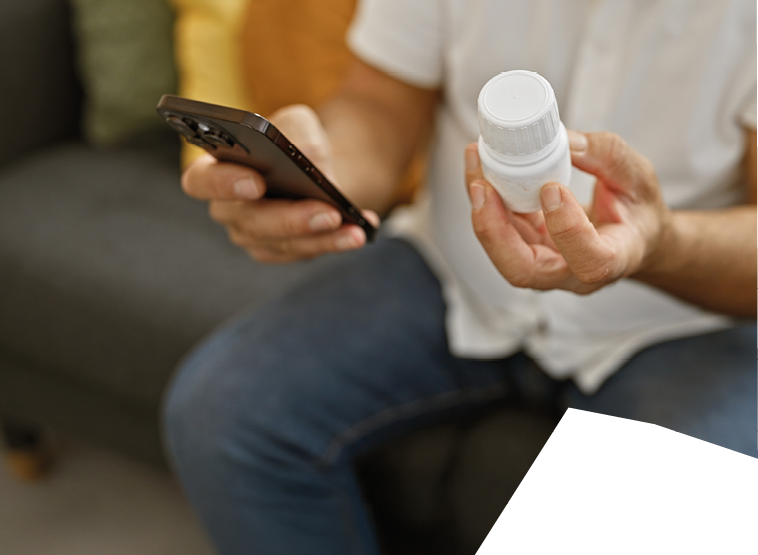 A man sitting on a couch holding a bottle. Description generated by AI