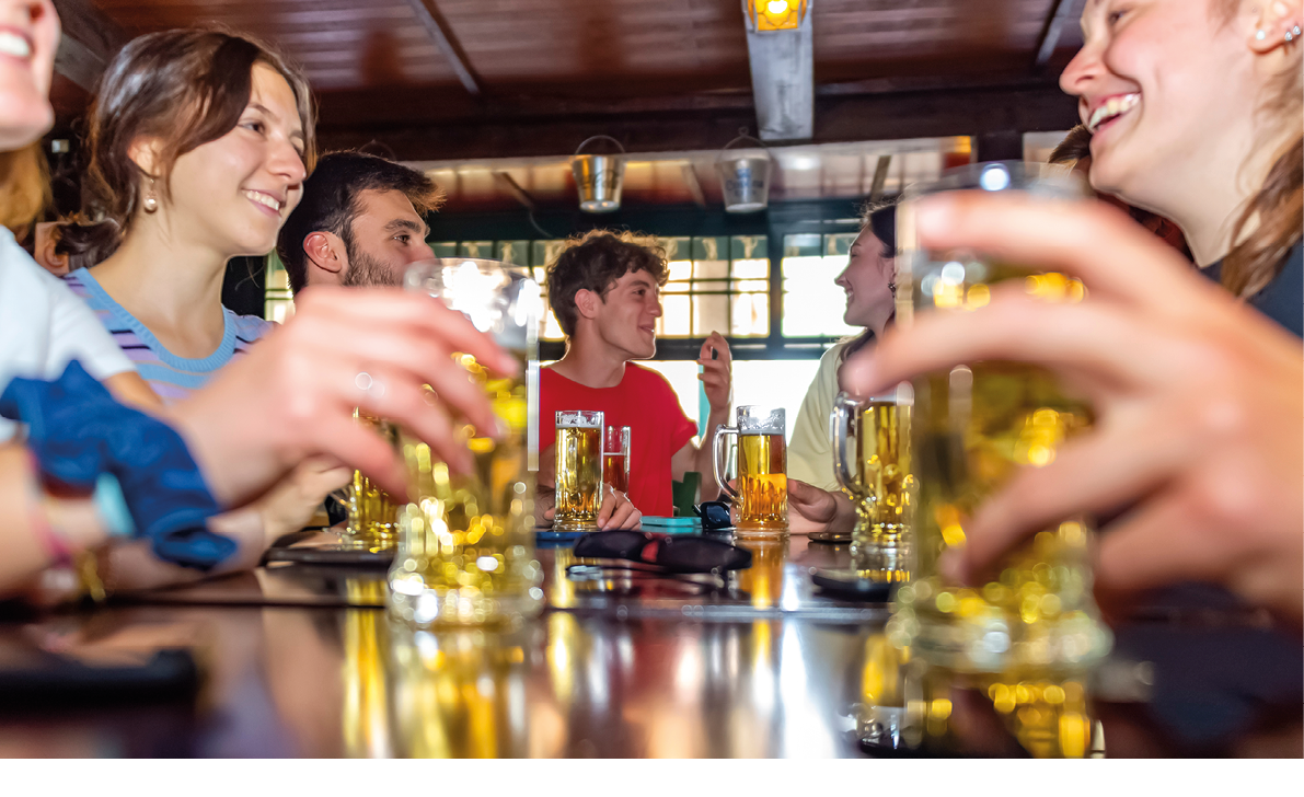 Group of millennials happy friends drinking beer in irish bar restaurant.