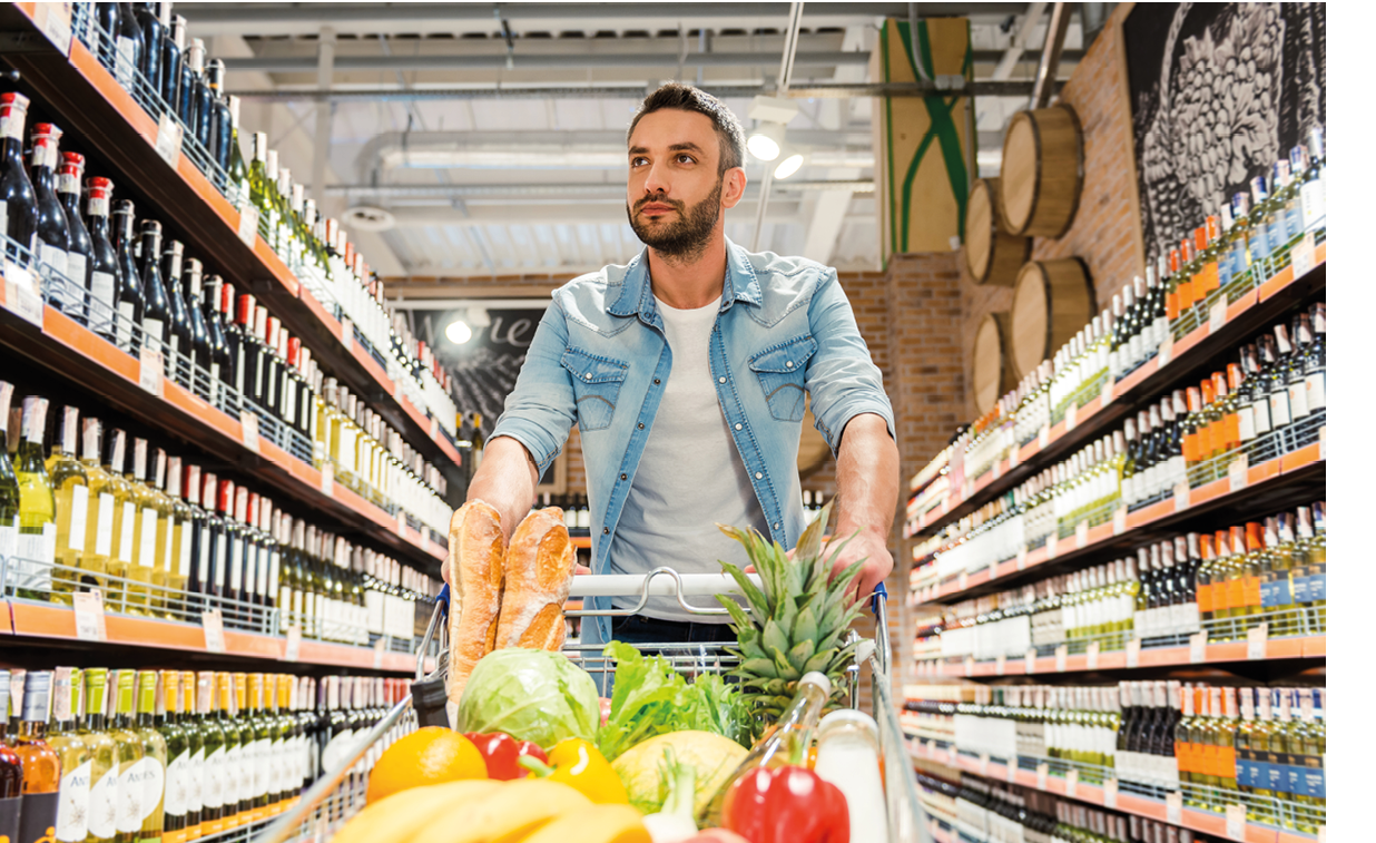 A man shopping in a grocery store with a cart full of fruits and vegetables. Description generated by AI