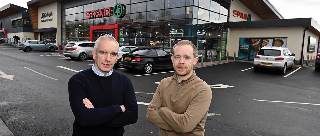 Two men standing in front of a store. Description generated by AI