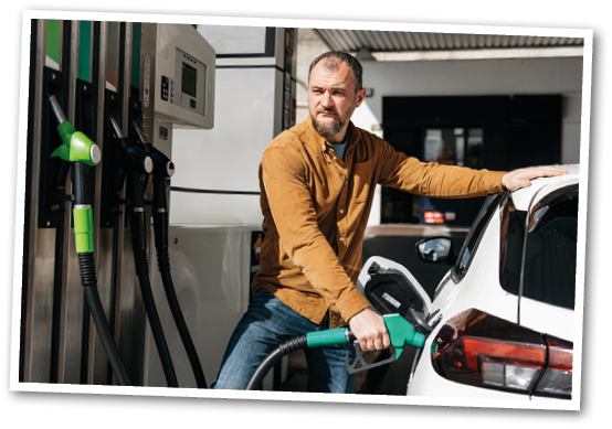 A man is pumping gas into his white car. Description generated by AI
