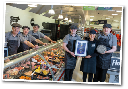 A group of people standing in front of a meat counter. Description generated by AI