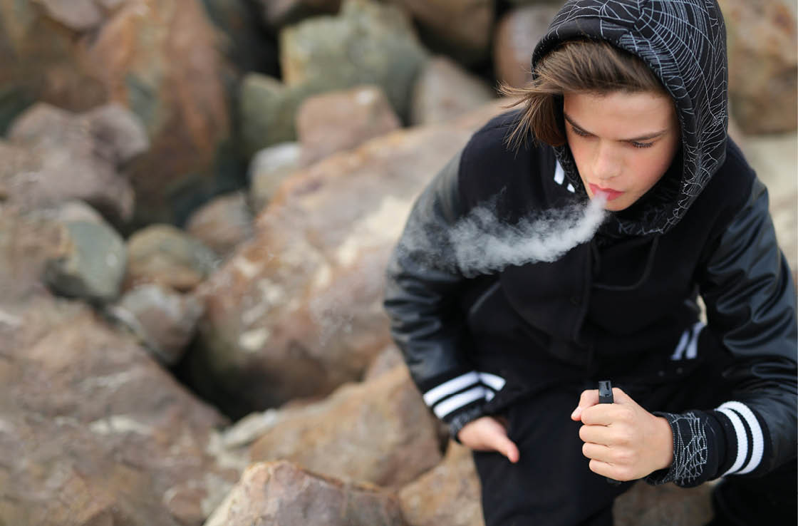 A boy smoking a cigarette. Description generated by AI