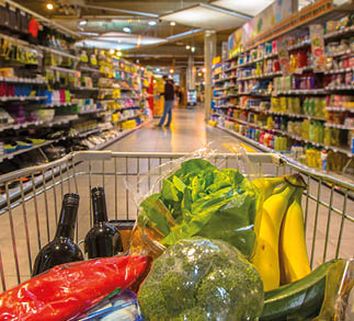 Supermarket trolley at an aisle filled up with healthy vegetables seen from the consumers point of view from above