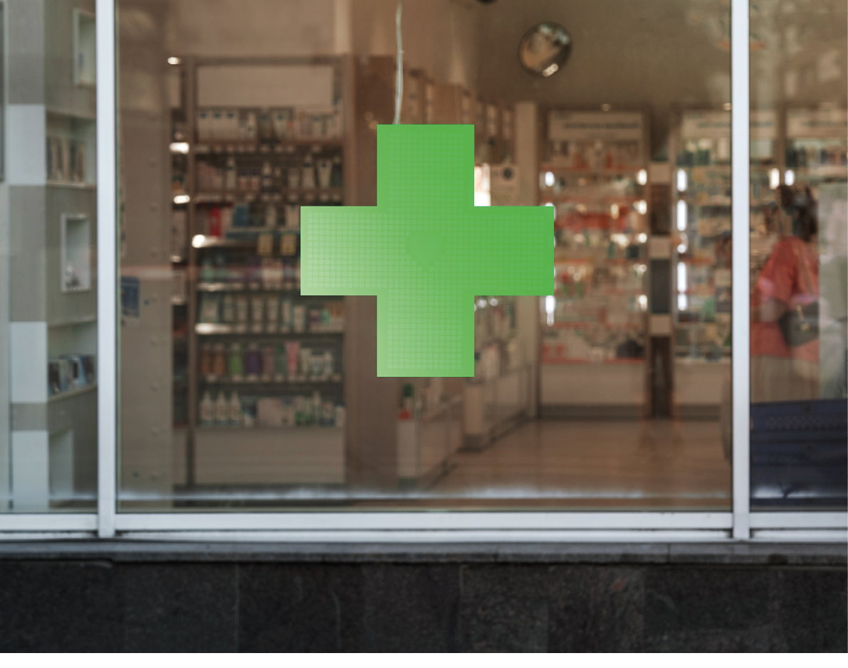 Green cross sign with neon light mounted on pharmacy shop window case outdoor