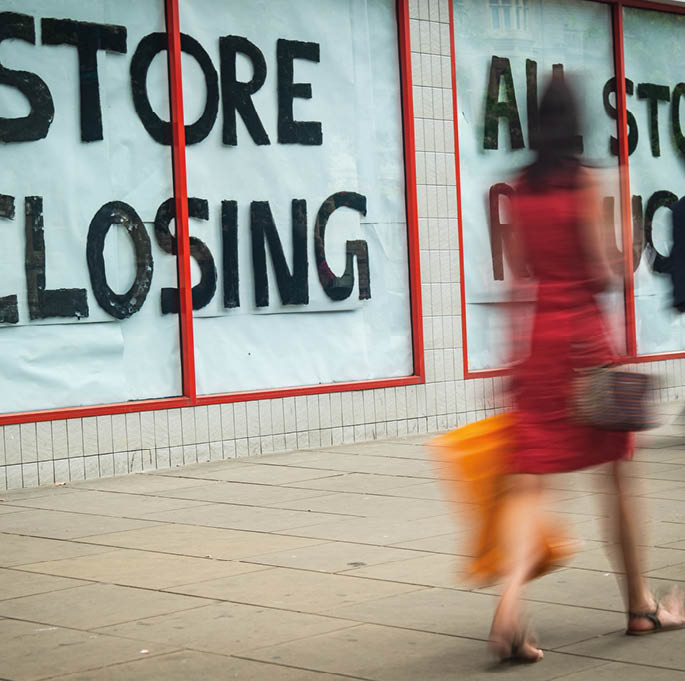 High Street 'Store Closing' sign with motion blurred shopper walking past