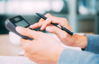 Close-up of male hands with pen using calculator