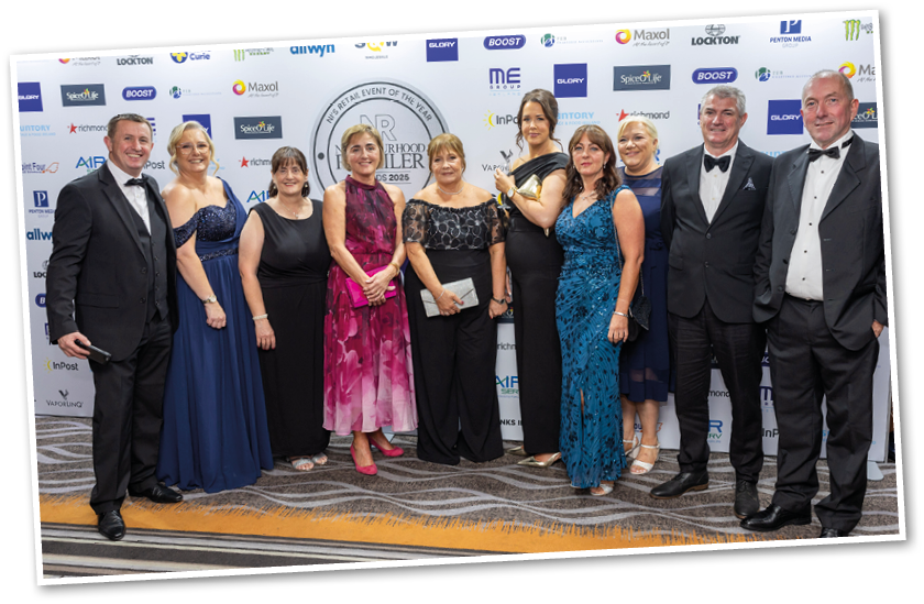 A group of adults dressed in formal evening attire stand together on a carpeted floor in front of a backdrop covered with logos at an event. Description generated by AI