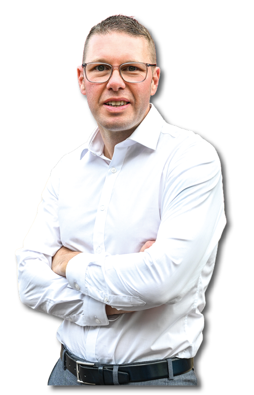 A person wearing glasses and a white button-up shirt stands with arms crossed and a slight smile against a white background. Description generated by AI