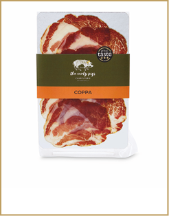 Packaged slices of coppa cured meat with a green and orange label from The Curly Pigs brand featuring a great taste award badge. Description generated by AI