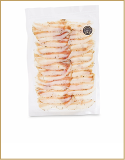 Vacuum-sealed package containing several slices of seasoned, cured meat with a small round label indicating a great taste award. Description generated by AI