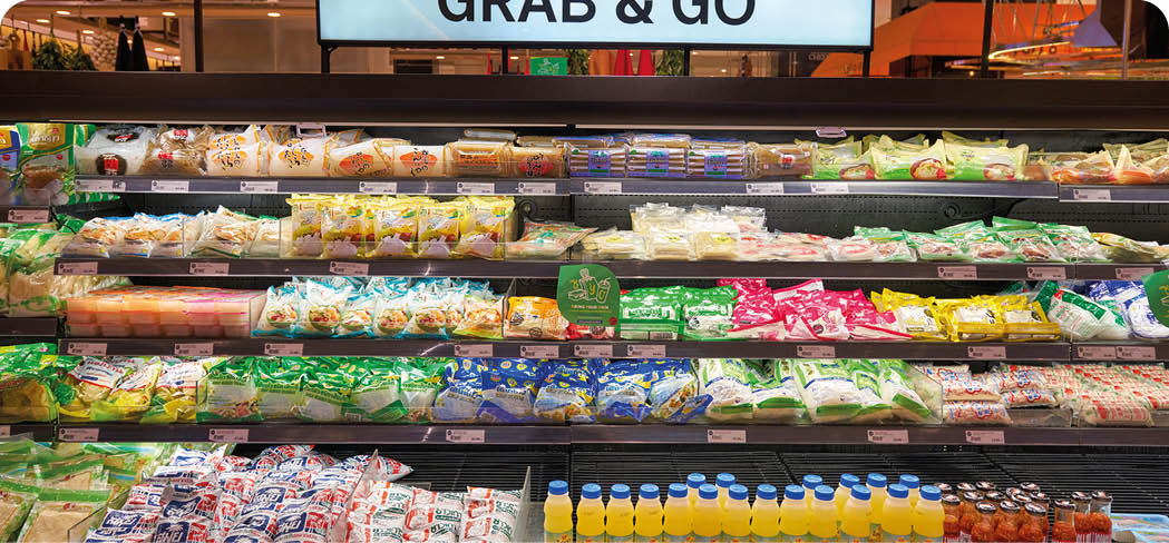 A supermarket refrigerated display case filled with various packaged dairy products, cheeses, and beverages arranged in neat rows under a sign that reads “GRAB & GO." Description generated by AI