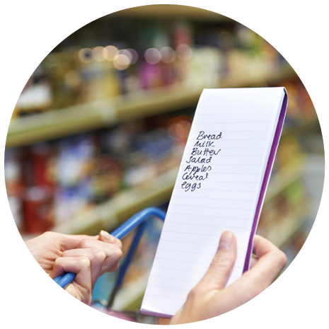A person is holding a shopping list with items written on it while pushing a shopping cart in a grocery store aisle. Description generated by AI