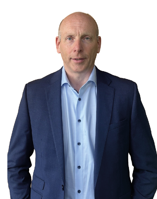 A person with short hair wearing a blue blazer over a light blue button-up shirt is standing against a white background. Description generated by AI