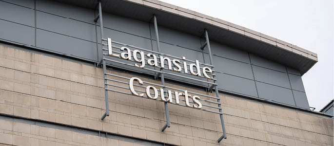 A building facade with a sign reading “Laganside Courts" mounted on a metal frame above a stone wall. Description generated by AI