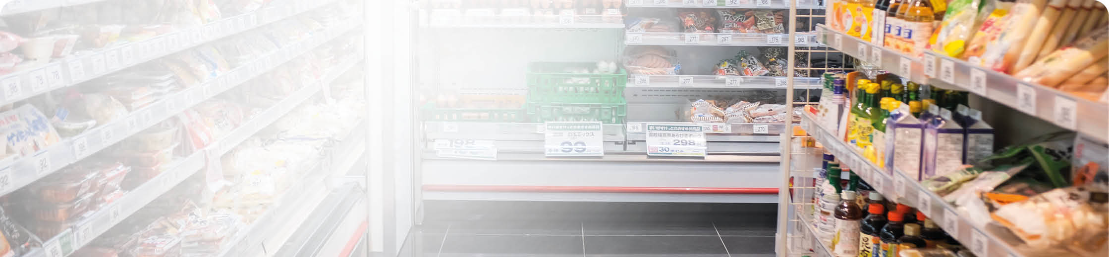 A person wearing dark clothing is stocking or arranging produce in a grocery store aisle with shelves filled with various packaged goods and fresh vegetables. Description generated by AI