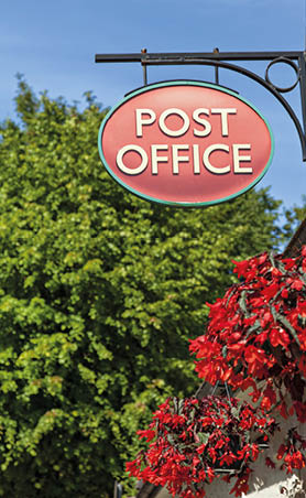 Image of an old fashioned post office sign in a rural location. 