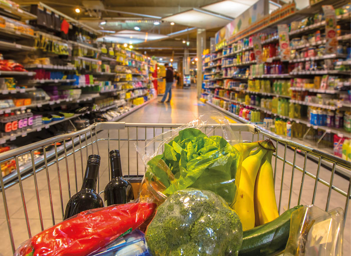 Supermarket trolley at an aisle filled up with healthy vegetables seen from the consumers point of view from above