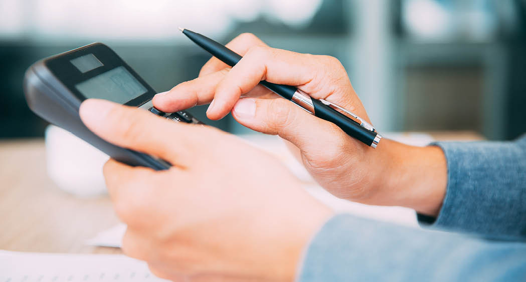 Close-up of male hands with pen using calculator