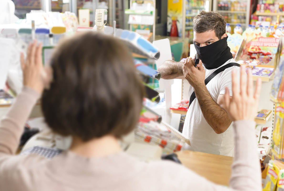 Masked thief pointing a gun to sales woman in a store