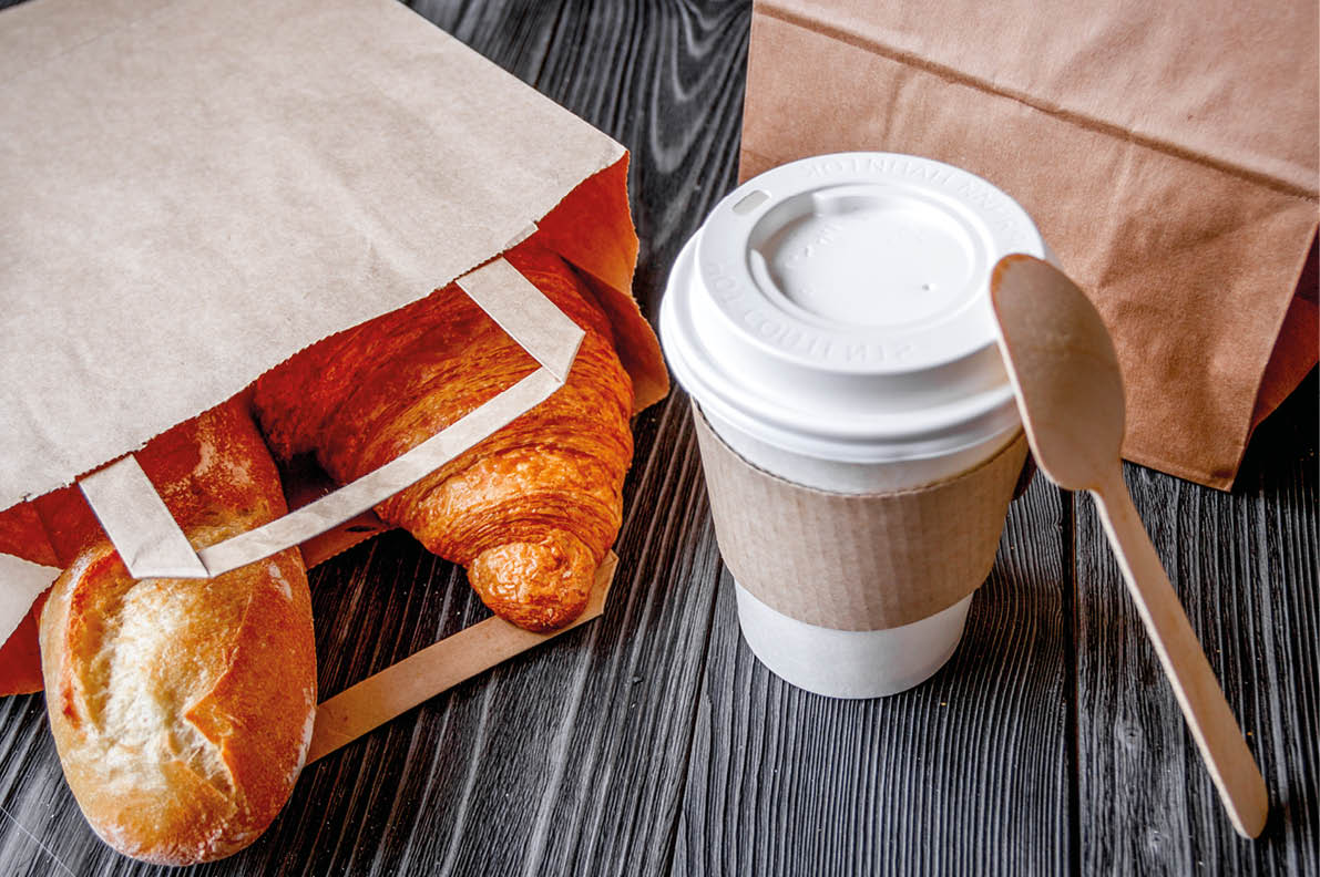 cup coffee and croissant in paper bag on wooden background
