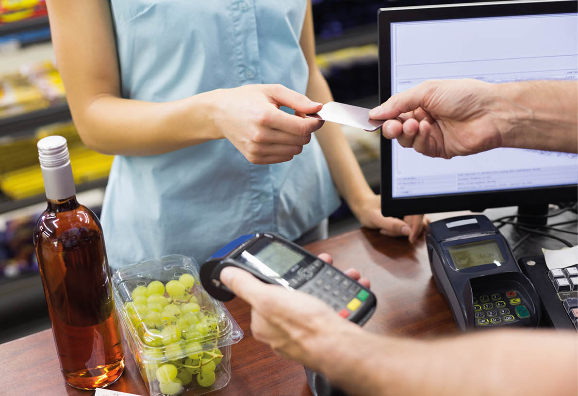 Woman at cash register paying with credit card in supermarket