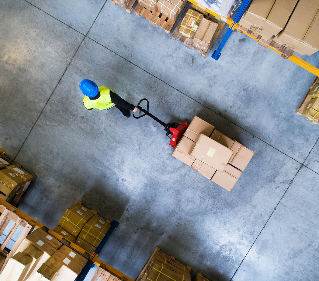 Male warehouse worker pulling a pallet truck.