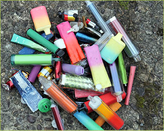 A collection of discarded electronic cigarette vapes have been collected and placed together over a worn concrete floor