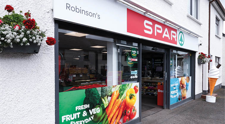 A storefront of Robinson's Spar convenience store with promotional signs for fresh fruit and vegetables and a large ice cream cone model outside. Description generated by AI