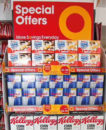 A store display features multiple boxes of Kinder Happy Hippo biscuits with a bright red and orange sign advertising special offers and savings. Description generated by AI