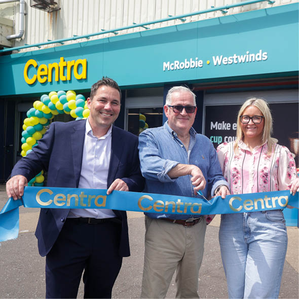 Four adults stand outside a store named Centra holding a blue ribbon with the store's name, appearing to celebrate a grand opening. Description generated by AI
