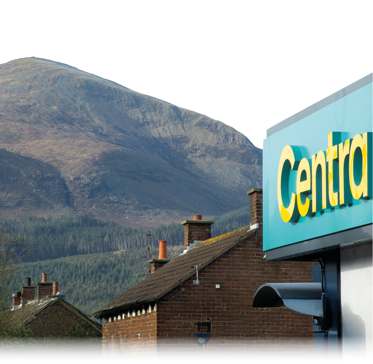 A large mountain rises behind rooftops with chimneys and a partial sign reading “Centra" on a building in the foreground. Description generated by AI