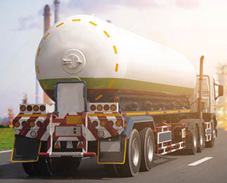 A large tanker truck is driving on a road toward an industrial refinery complex with tall structures and pipes during sunset. Description generated by AI