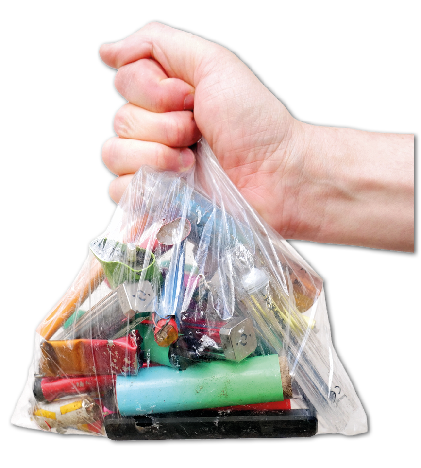 A hand is holding a clear plastic bag filled with various used batteries. Description generated by AI