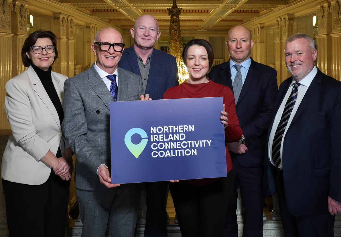 A group of six people are standing in a hallway, holding a sign that says “Northern Connectivity". AI generated content