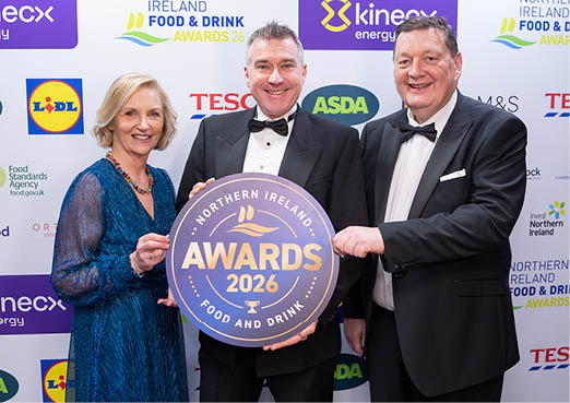 Three people are standing in front of a sign that says “Northern Ireland Food & Drink Awards 2012". They are holding a trophy together. AI generated content
