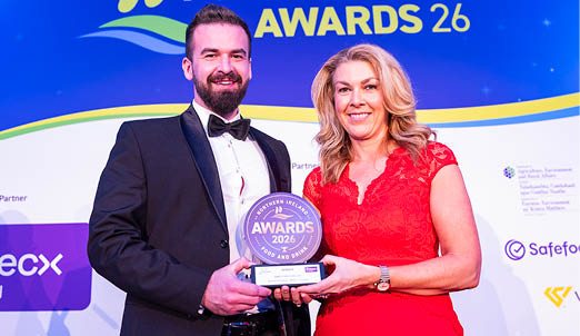 A man and woman are standing on stage holding an award. The man is wearing a suit and bow tie. AI generated content