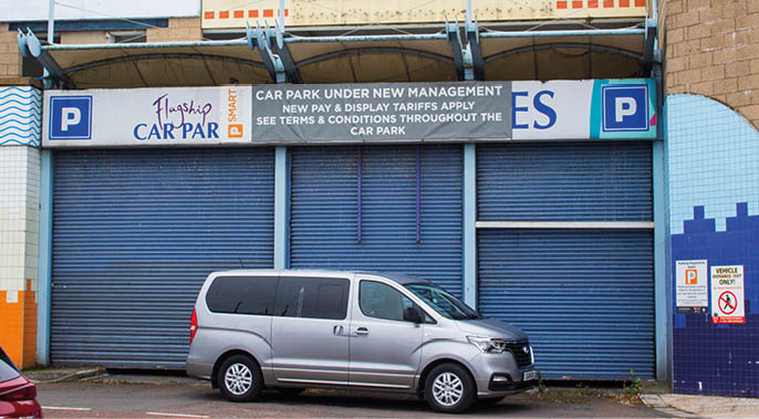 A silver car is parked in front of a building with a blue door. AI generated content
