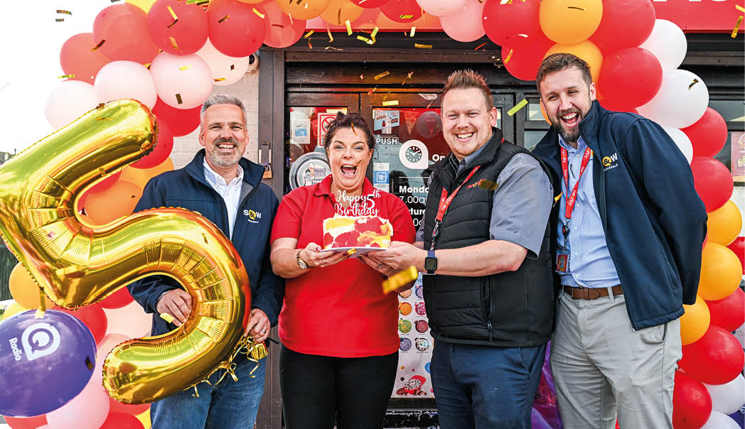 Four people are standing in front of a balloon arch, celebrating a birthday. AI generated content