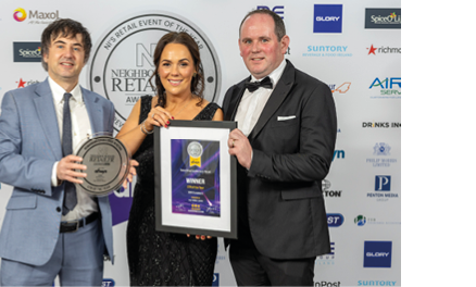 Three people are standing in front of a sign. A man and a woman are holding an award. The woman is wearing a black dress. AI generated content