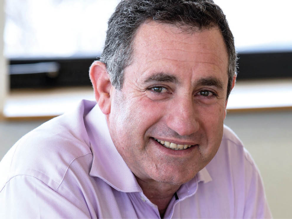 A man wearing a purple shirt is smiling at the camera. AI generated content