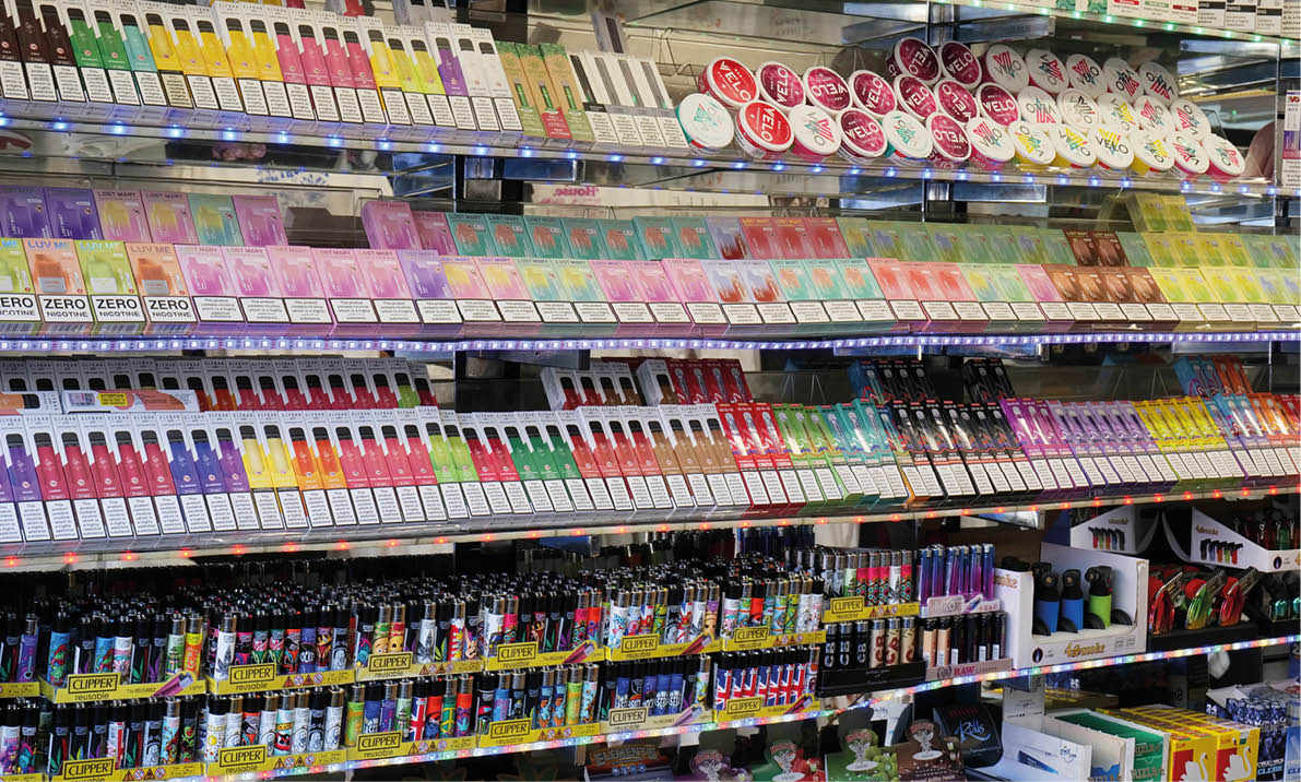 London, UK 08 28 2024 Rows of vibrant disposable electronic cigarette vapes and lighters stacked on shelves in a tourist shop in the city