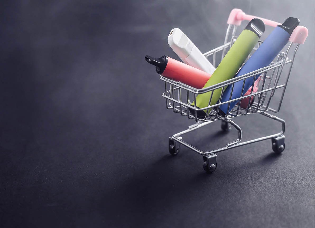 Disposable vapes in a shopping cart on a black background. Modern electronic cigarettes.