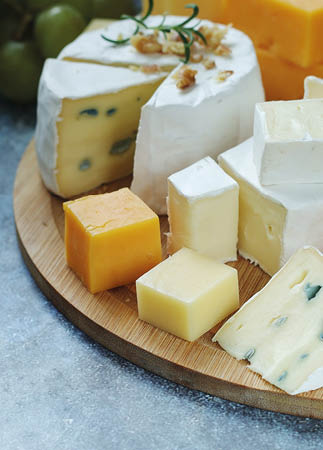 Several types of cheese served with honey and grapes